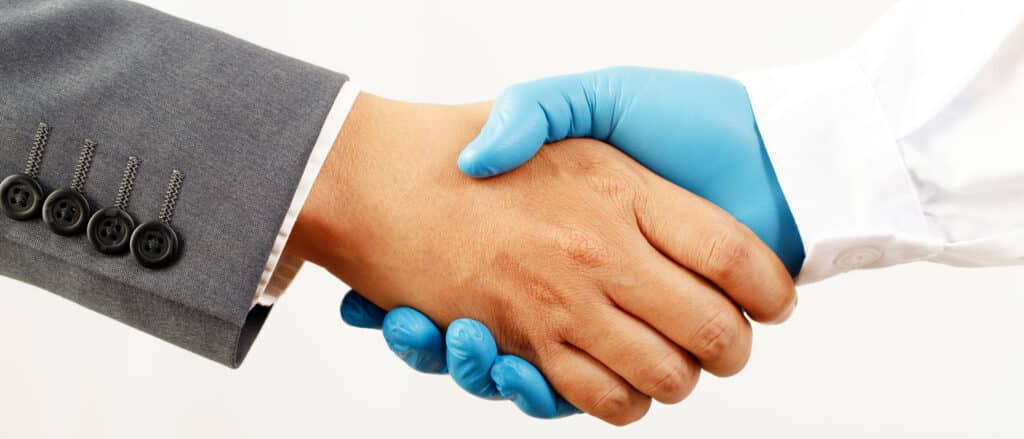 A business man and scientist shake hands to signify the recognition that healthcare and caregiving are the responsibility of both employee and employer.